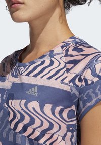 Sportovní tričko s krátkým rukávem s růžovo-modrým abstraktním vzorem, kulatým výstřihem a stříbrným logem Adidas. Texturovaná látka.