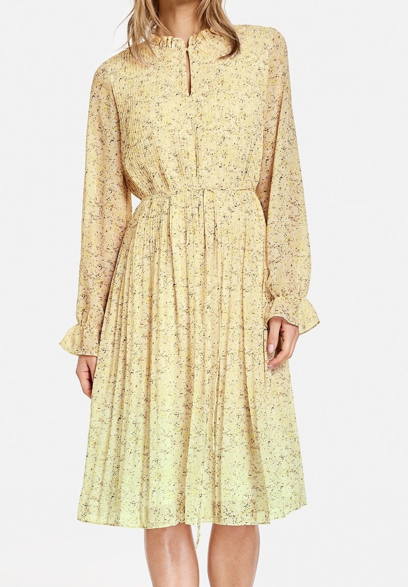 Gul blomster-midi-kjole med lange ærmer, rynket krave, nøglehul-udskæring og elastisk talje. Letvægtsstof med tekstureret finish.