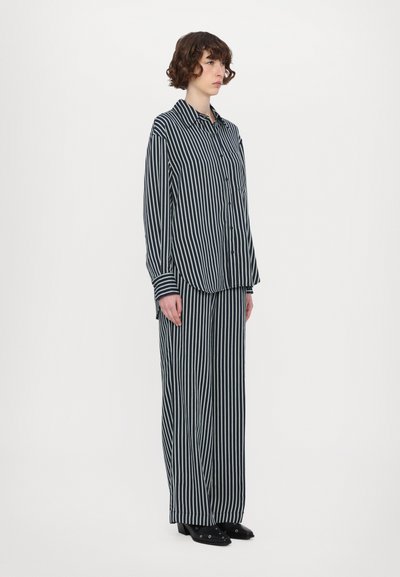 Striped pajama set featuring a button-up collared shirt and wide-leg pants. Material appears soft, in navy and white stripes, with long sleeves.