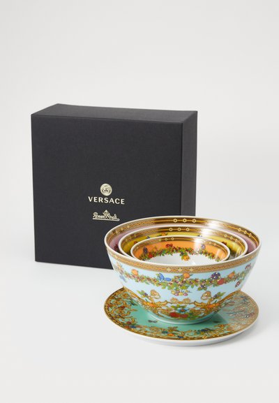 Štyri dekoračné misy rôznych veľkostí s kvetinovými vzormi, zlatými akcentmi a tyrkysovým tanierom, prezentované v čiernej krabičke Versace.