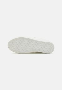 Sneaker sole in white rubber with a geometric pattern and raised texture, featuring a rounded toe and subtle side accents.