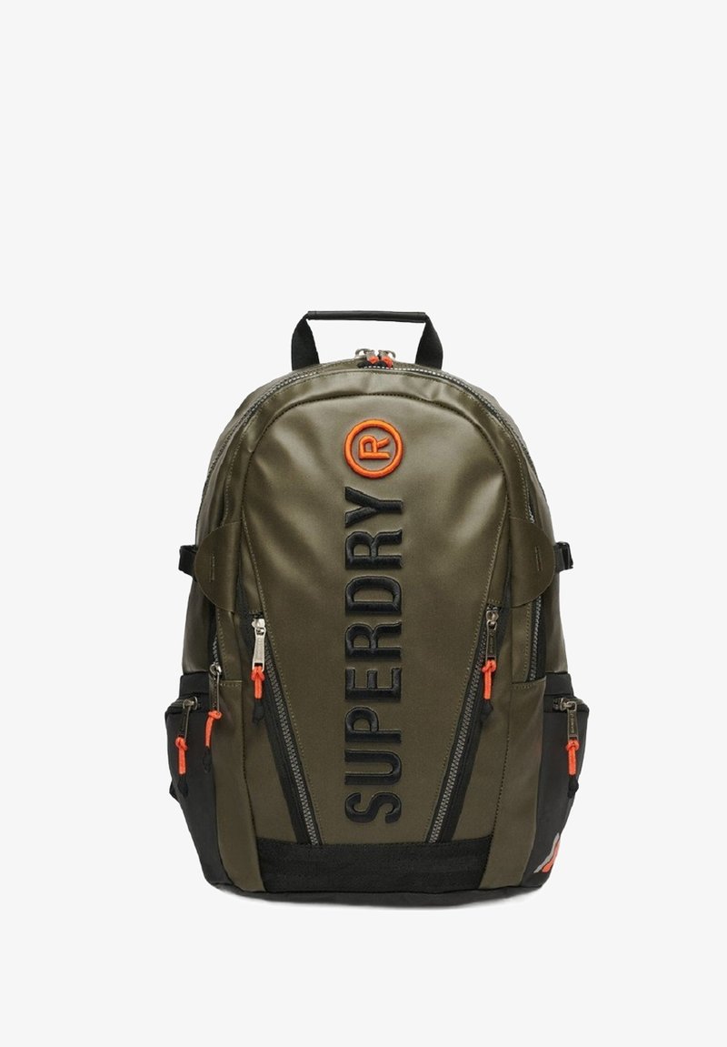 Sac à dos vert olive avec accents noirs, arborant le logo "SUPERDRY" en évidence, des tirettes de fermeture éclair orange et de multiples compartiments zippés.