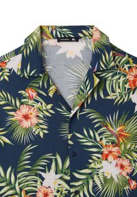 Camicia a maniche corte di colore blu navy con un vivace motivo floreale tropicale, che presenta ibischi e foglie di palma, colletto con bottoni e tessuto leggero.