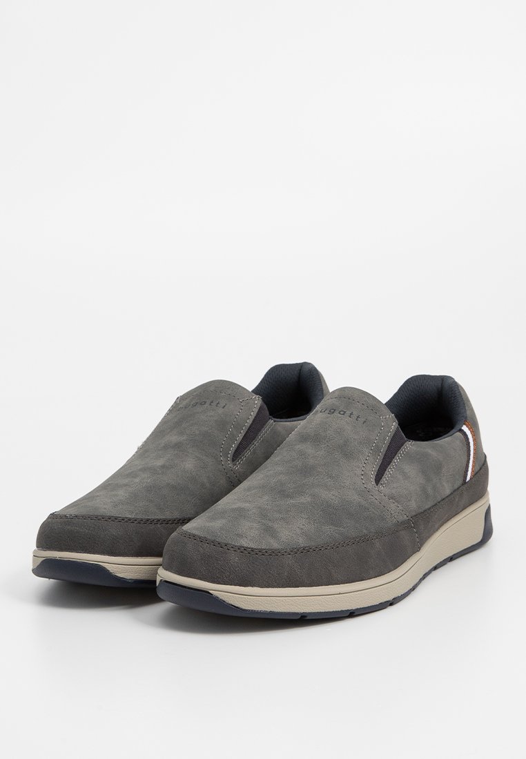 Chaussures grises à enfiler en daim avec des panneaux latéraux élastiques, une semelle beige et un branding discret. Le design est bas et texturé.