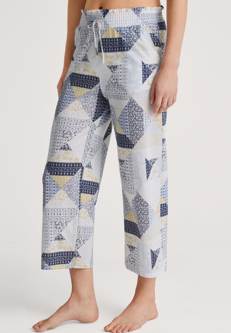 Blauwe en witte gestreepte cropped broek met een trekkoord in de taille, voorzien van geometrische vormen en bloemaccenten in marineblauw en geel.