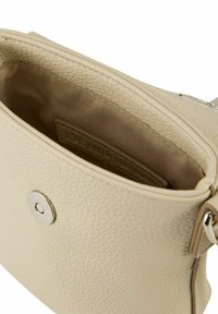 Wnętrze beżowej skórzanej torby na ramię z teksturowaną powierzchnią, srebrnym zapięciem na zatrzask i podszewką z materiału. Brak widocznych dodatkowych kieszeni.