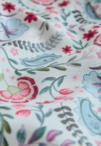 Kvetinová tkanina so štruktúrovaným vzorom; obsahuje červené, ružové, modré a zelené kvety a listy na svetlom krémovom podklade.