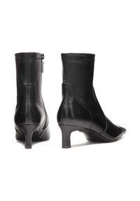 Crne kožne čizme do gležnjeva s šiljastim vrhom, uskim potplatom, zatvaranjem na patentni zatvarač sa strane, i elegantnim, glatkim završetkom.