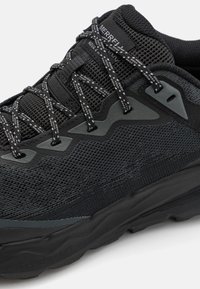 Chaussure de randonnée noire avec une tige en mesh et des superpositions texturées, un laçage renforcé et une semelle noire rembourrée pour traction et confort.