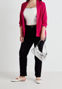 Rosa kavaj, vit cropped topp, svarta jeans och vita slideskor med prickar. Håller en liten silverhandväska med kedjedetaljer.