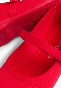 Rode canvas schoenen met een band, met een gladde textuur en een ronde neus, zichtbare stiksels en een getextureerde rubberen zool.