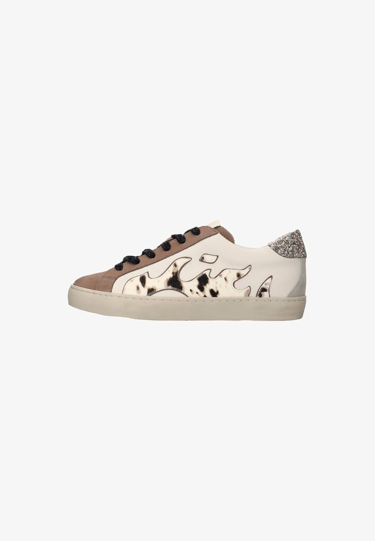 Zapatilla baja con paneles beige y marrón claro, cordones negros, diseño de estampado de vaca en los laterales y detalle de talón plateado brillante.