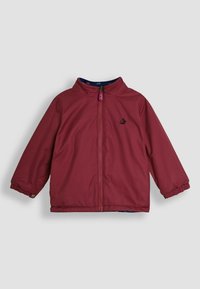 Burgundi vízálló dzseki magas gallérral, elöl cipzárral, rugalmas mandzsettákkal és egy kis fekete logóval a mellkason. Sima textúra.