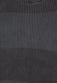 Gros plan sur un tissu en tricot foncé avec une texture côtelée et un motif vertical subtil.