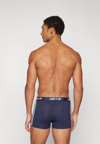 Navy blue boxer briefs with a snug fit, featuring a contrasting white Adidas logo on the waistband and three white stripes on the sides.