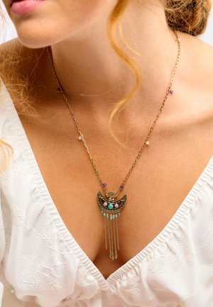 Collier chaîne en or avec pendentif en forme de croissant de lune orné de perles turquoise, roses et violettes ; des chaînes tombantes pendent en dessous.