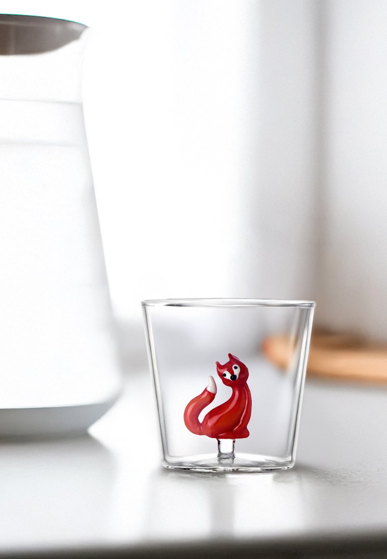 Przezroczysty szklany kubek z czerwonym, kreskówkowym wzorem lisa w środku, z błyszczącym wykończeniem i gładkimi krawędziami. Prosta, nowoczesna forma.