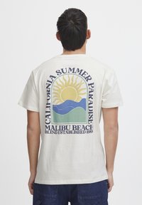 Kremo spalvos medvilninė marškinėlė su saulės grafika virš mėlynų ir žalių bangų, su užrašais "Kalifornijos vasaros rojus" ir "Malibu paplūdimys".