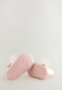 Helle rosa Kleinkinderschuhe mit einer strukturierten, glitzernden Oberfläche, gemusterten Sohlen und dekorativen Netzdetails an der Ferse.