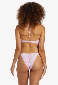Bikini rosa con motivo floreale, con lacci regolabili al collo e chiusura sul retro. Presenta un modello di slip a gambe alte.