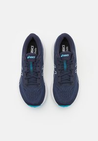 Scarpe sportive blu navy con tomaia in rete traspirante, suola bianca e accenti turchesi sui lacci e nel branding. Presentano una superficie testurizzata.