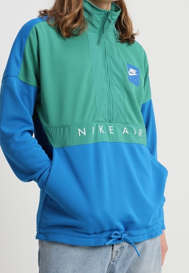 Nike Air lättviktig jacka i teal och blå, med hög krage, kvart zip och justerbar fåll med dragsko. Logotypen visas fram.