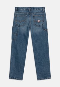 Jeans in denim blu medio con una vestibilità rilassata, dotati di due tasche posteriori, una tasca laterale cargo e dettagli di cucitura a contrasto.