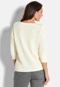 Hellgelbe Strickjacke mit lockerem Schnitt, Dreiviertelärmeln und strukturiertem Muster, mit weitem Ausschnitt und rippenförmigem Saum.