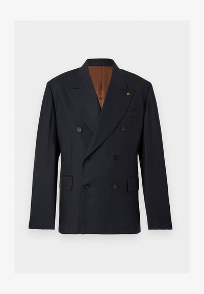 Μαύρο σακάκι διπλής σειράς με μυτερούς γιακάδες, έξι κουμπιά, μπροστινές τσέπες με καπάκια και καφέ εσωτερική επένδυση σε απλό φόντο.