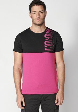 Crno-roza T-shirt s kratkim rukavima u boji blokovima, sa grafičkim printom na lijevoj strani i okruglim izrezom.