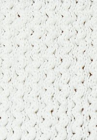 Biała dziana tkanina o teksturowanym wzorze, z splatanymi pętlami i podniesionymi powierzchniami, tworząca miękki i gęsty wygląd.