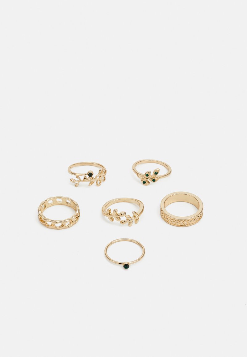 Conjunto de seis anéis dourados com vários designs: trançados, com motivos de folhas e bandas sólidas; alguns com detalhes em pedras preciosas verdes.