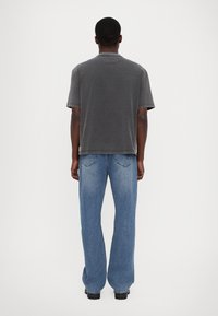 Grå bomulds t-shirt med korte ærmer, boxy pasform og rund halsudskæring, parret med lyseblå vide denim jeans.