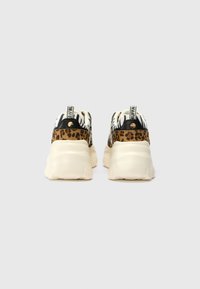 Ténis chunky apresentando uma mistura de padrões animais, predominantemente leopardo e zebra, com uma sola de borracha creme e detalhes em preto.