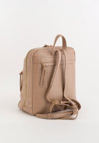 Beżowy, skórzany plecak z tłoczeniem imitującym skórę krokodyla, o usztywnionym kształcie, ze złotymi zamkami i regulowanymi paskami na ramiona. Dwie przednie kieszenie zapinane na zamek.