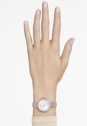 Runde Uhr mit Roségold-Gehäuse und Diamantakzent an einem silbernen Mesh-Armband; weißes Zifferblatt mit einfachen Stundenmarkierungen und Zeigern.