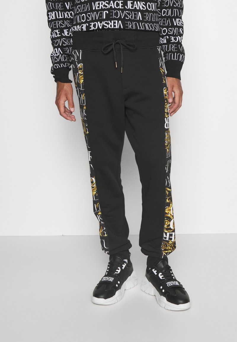 Versace Jeans Couture LOGO BAROQUE - Tracksuit bottoms - black/gold ...