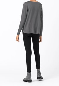 Harmaa pitkähihaiseksi ylhäältä väljä, mustat slim fit -housut ja harmaat nauhalliset nilkkurit. Tasainen kangas, yksinkertainen muotoilu.