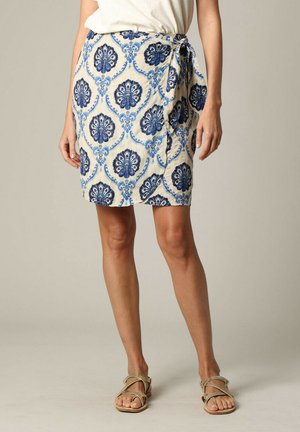 Jupe enveloppante présentant un motif floral bleu et blanc, fabriquée en tissu léger, avec une fermeture à nouer sur le côté et un design à la longueur genou.