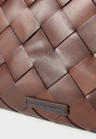 Textura din piele împletită maro, cu un mic etichetă embosată Loeffler Randall în colțul de jos.
