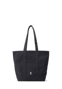 Zwarte canvas tote bag met twee lange handvatten, een voorvak en een klein logo-label nabij de onderkant. Eenvoudig ontwerp, ruime vorm.
