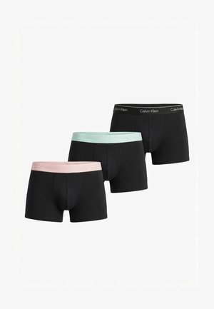 Trois paires de boxers noirs pour hommes avec ceintures élastiques en rose pastel, vert menthe et noir, chacune estampillée Calvin Klein.