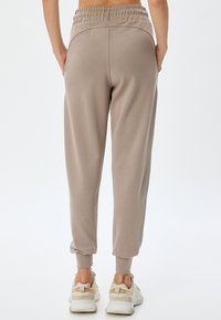 Lysebrune sweatpants med elastisk talje, sidelommer og tapered manchetter; glat stof med en afslappet pasform.