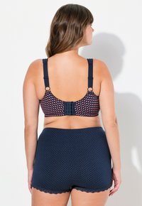 Marinblått underklädeset med polka prickar som inkluderar en vadderad bralette med rosa prickar och justerbara remmar, tillsammans med matchande shorts med spetsdetaljer.