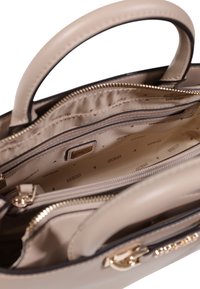 Borsa a mano in pelle beige con doppi manici, accessori in metallo dorato, molteplici scomparti interni e una fodera in tessuto decorato.