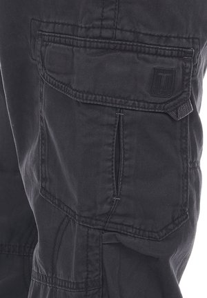 Schwarze Cargo-Hose aus strapazierfähigem Stoff, mit mehreren Taschen, sichtbaren Nähten und einem Logo-Patch auf der linken Seite.