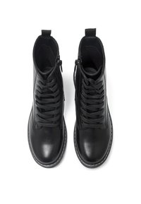 Bottes cheville en cuir noir à finition lisse, dotées de lacets et d'une fermeture éclair latérale, avec des coutures blanches autour de la semelle.