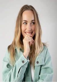 Mintgroene corduroy jas met een gestructureerd oppervlak, grote knopen en een kraag, gedragen door een vrouw met lang, golvend haar.