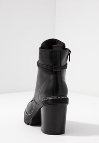 Svart läder ankle boot med dragkedja, rund tå och kraftig klack. Har ett tygdetalj runt ankeln och kontrasterande sömmar.