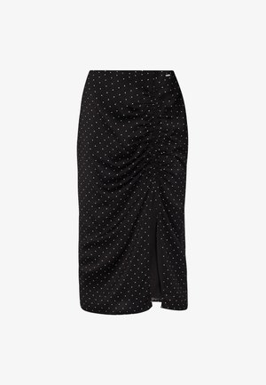 Falda midi negra con lunares blancos. Presenta fruncido recogido en un lado y una abertura frontal, elaborada con una tela suave y ligera.